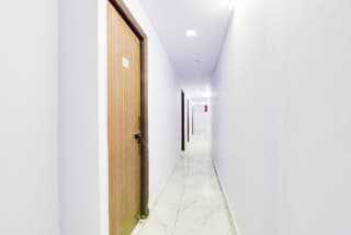 Well-lit hallway with a brown door leading to a room.